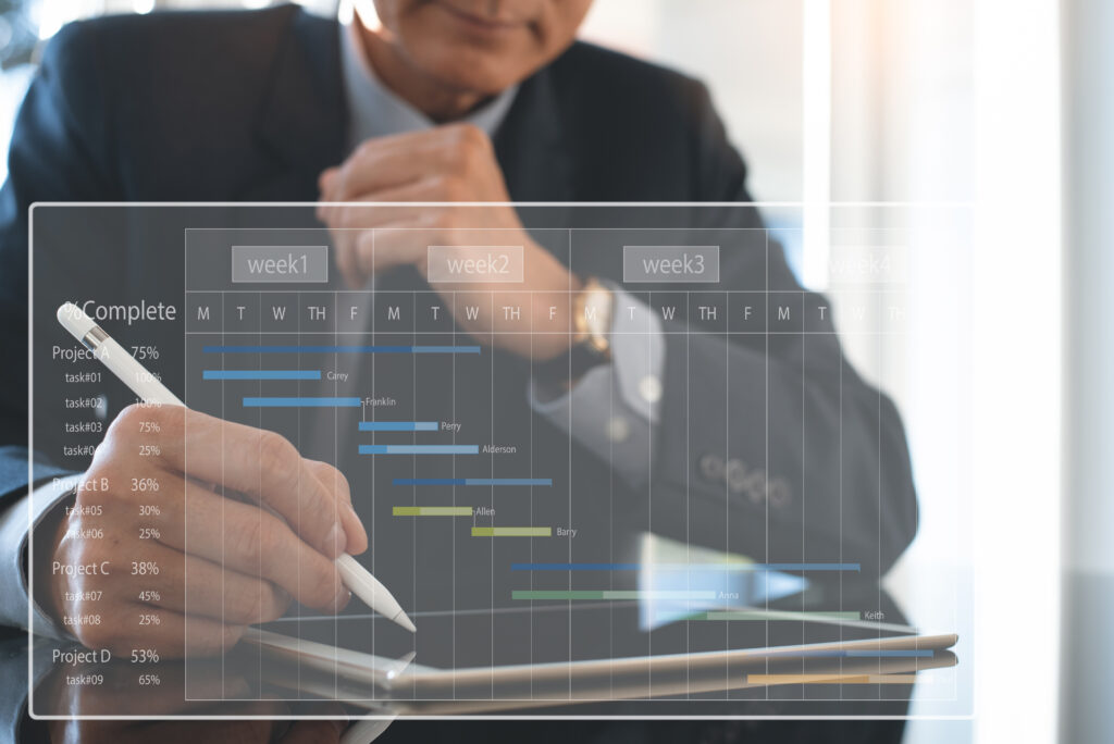 Project management. Project manager updating tasks and milestones progress planning with augmented reality Gantt chart scheduling on virtual screen. Asian businessman working on digital tablet and laptop computer at office